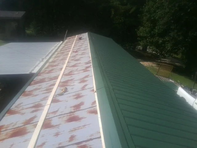 Old rusted panels beside newly installed green metal roofing — Wind Damage Roof Repair by Roofing Brothers in Interlaken