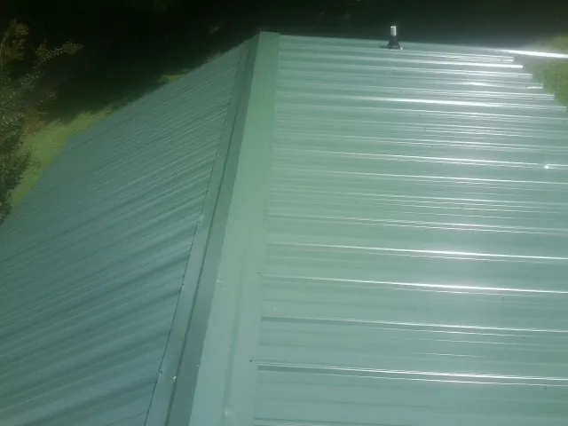 New green metal panels meeting at the ridge of a roof — Flat Roof Repair work by our crew in Interlaken
