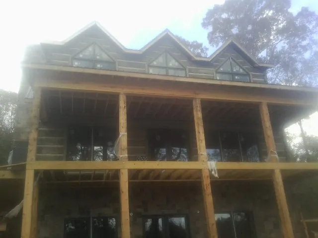 Dormers and porch framing on a large log home under construction — Roof Coating work by our crew in Interlaken