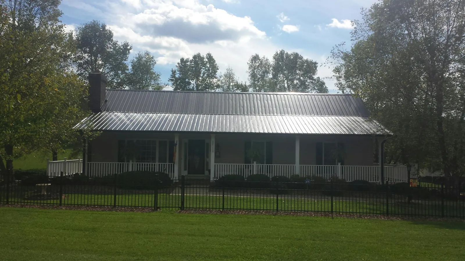 Gray metal roof on a brick ranch with a full width front porch — Gutter Guard Installation work by our crew in Interlaken