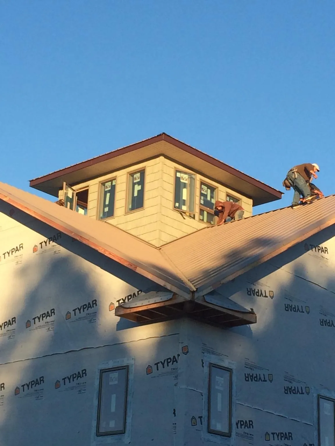 Roofers working around a rooftop cupola on a new metal roof at sunset — Roof Waterproofing in Interlaken by Roofing Brothers